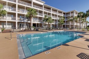 Un hotel con piscina, varios balcones y palmeras.