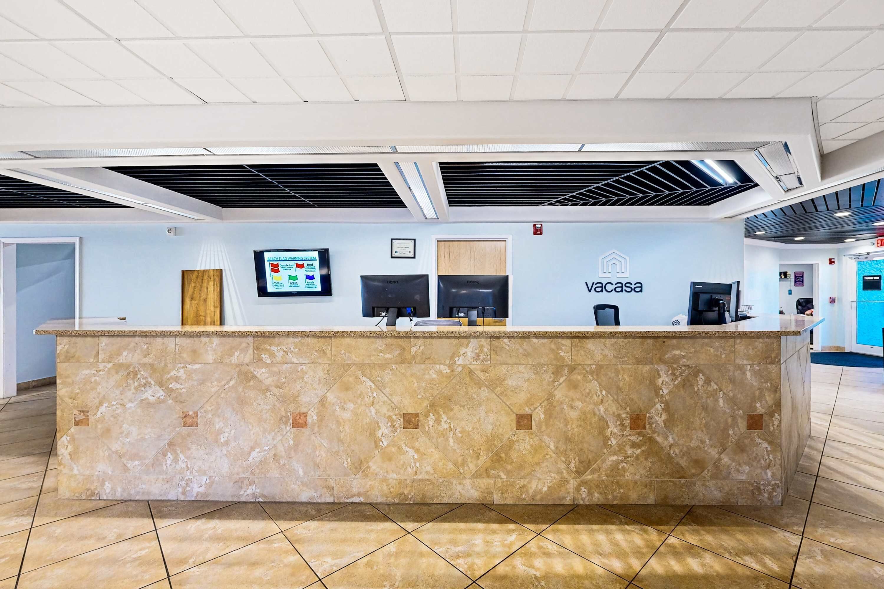 A reception desk with a marble top, a digital screen, and a sign that reads "vacasa."