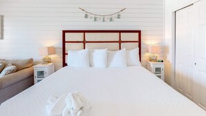 A neatly made bed with white linens, a wooden headboard, and two bedside lamps. - Modern oceanfront studio with pool access, central AC, and beach service (Fort Walton Beach)