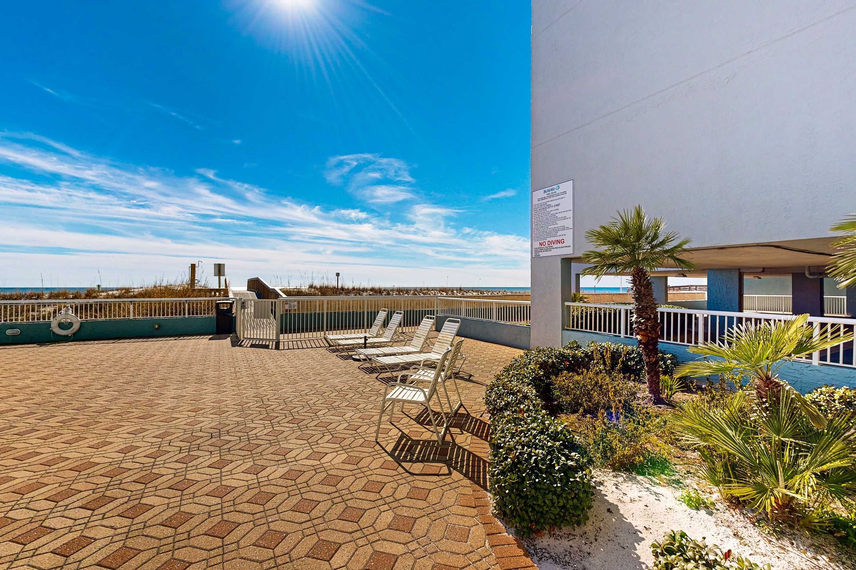 A rooftop terrace with sun loungers, a pool, and a view of the ocean.
