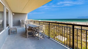 A balcony with a table and chairs overlooking a beach. - Great beachfront condo with pool, tennis, & W&D - quick drive to dining (Fort Walton Beach)
