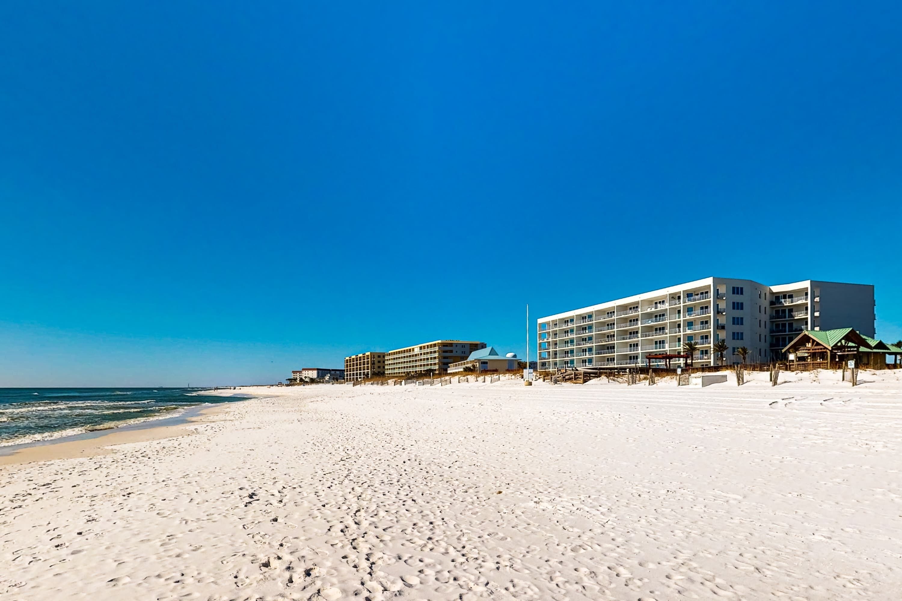 A beach with a hotel in the background.