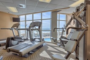 A gym with cardio machines, weight machines, and a large window offering a view of the ocean. - Fifth-Floor, Gulf-Front Condo w/ Balcony, Beach Access & Shared Pools/Hot Tub (Perdido Key)