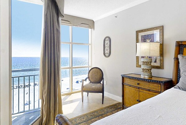 A bedroom with a large window, a chair, a bedside table with a lamp, and a bed. - Fifth-Floor, Gulf-Front Condo w/ Balcony, Beach Access & Shared Pools/Hot Tub (Perdido Key)