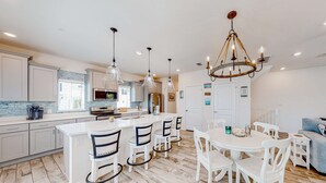 Une cuisine moderne avec des meubles blancs, un îlot central et des luminaires suspendus.