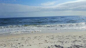 Une plage où l’on peut voir des empreintes de pas dans le sable, avec l’océan en arrière-plan.