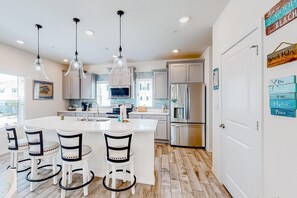 A modern kitchen with a central island, pendant lights, and a refrigerator. - Dog-friendly townhouse with private beach, hot tub, pool, tennis, golf, gym, AC (Perdido Key)
