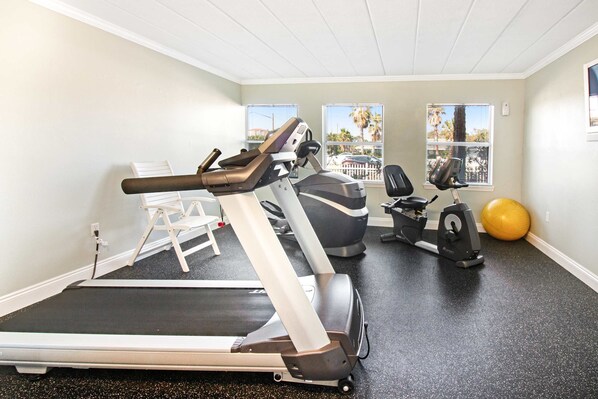 Une salle de sport équipée d’un tapis de course, d’un vélo d’appartement et d’un ballon d’exercice.