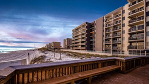 A beachfront hotel with multiple balconies, a wooden boardwalk, and a sandy beach. - Gulf-front condo with heated pool, fitness room & beach chairs - close to dining (Fort Walton Beach)
