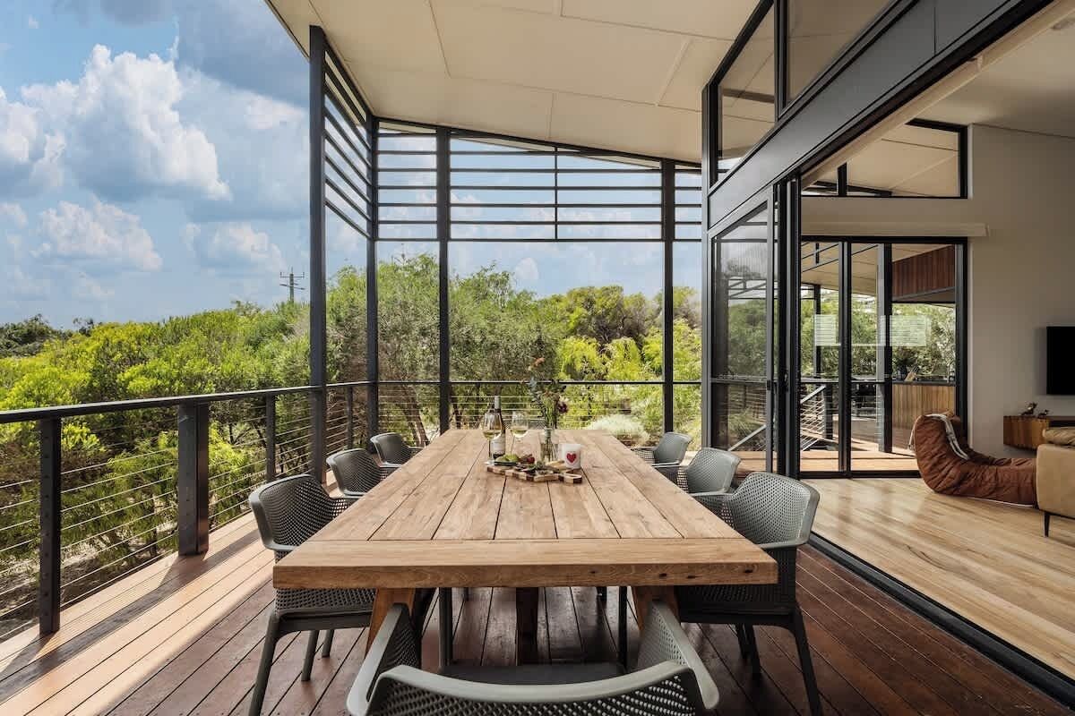 A wooden deck with a dining table and chairs, a sofa, and a TV.