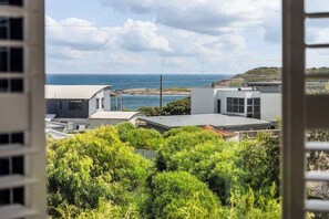 A coastal residential area with modern buildings, a view of the sea, and lush greenery.