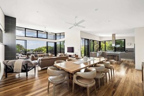 A spacious living area with a large wooden dining table, comfortable seating, and a view of the outdoors.