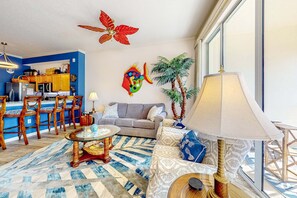 Ein Wohnzimmer mit einer Couch, einem Couchtisch, einer Lampe und einer Wanddekoration mit Fischen.