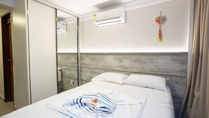 A hotel room with a bed, a wardrobe, an air conditioning unit, and a decorative wall hanging. - Mar Bello Plaza #207 por Carpediem (Cabedelo)