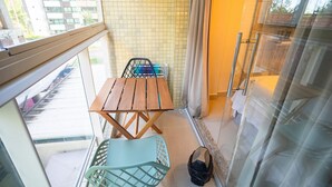 A balcony with a table and chairs, a trash bin, and a view of the street. - Mar Bello Plaza #207 por Carpediem (Cabedelo)