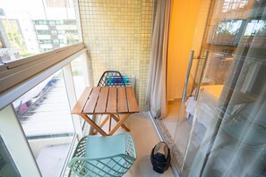 A balcony with a table and chairs, a trash bin, and a view of the street. - Mar Bello Plaza #207 por Carpediem (Cabedelo)
