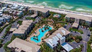 Luchtbeeld van een resort met meerdere gebouwen, een zwembad en een strand.