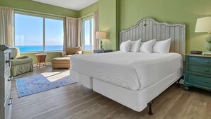 Um quarto espaçoso com uma cama grande, vista para o oceano e uma parede verde.