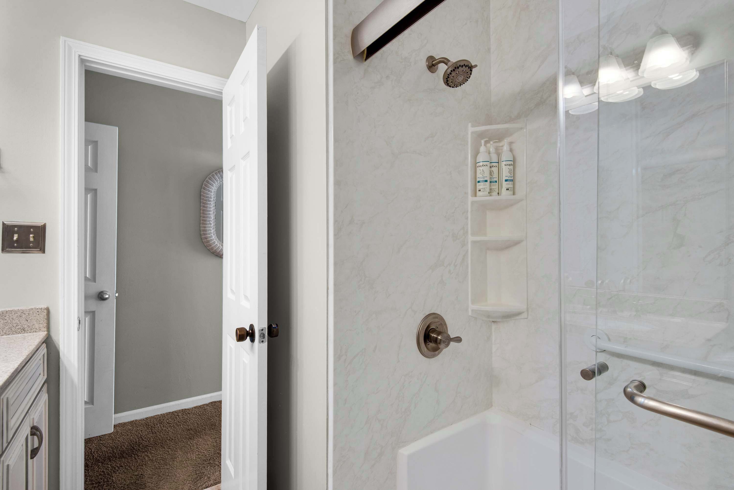 A bathroom with a shower, a towel rack, and a shelf with toiletries.