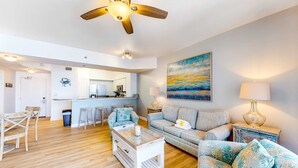 Ein geräumiges Wohnzimmer mit Holzboden, Deckenventilator, einer Couch, einem Couchtisch und einem Gemälde an der Wand.
