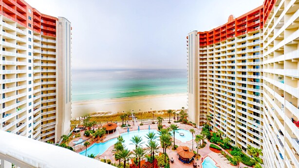 Ein Hochhotel mit Poolbereich und Blick auf den Strand.