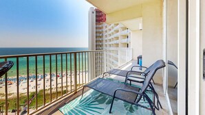 Un balcón con vista a la playa y al océano, con dos sillas y una mesa.
