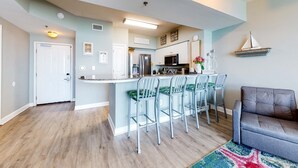 Una cocina moderna con una isla central, taburetes de bar y un comedor con sillas.