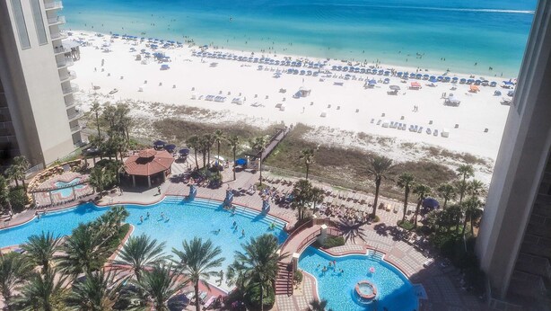 Un resort con piscina, playa y palmeras.