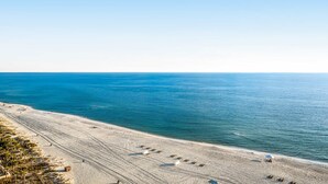 Une plage avec un ciel dégagé, un rivage sablonneux et quelques parasols.