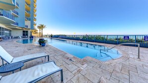 A pool area with lounge chairs, a pool, and a building with balconies. - Updated beachfront retreat with hot tub, outdoor pool & balcony (Panama City Beach)
