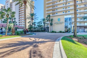 A hotel entrance with a brick pathway, palm trees, and a building labeled "STERRING BEACH". - Gulf-front Condo w/ Shared Pool & Hot Tub, Ocean Views, WiFi, and Washer/Dryer (Panama City Beach)