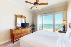 A hotel room with a large bed, a wooden dresser, a television, a plant, and a balcony with a view of the ocean. - Gulf-front Condo w/ Shared Pool & Hot Tub, Ocean Views, WiFi, and Washer/Dryer (Panama City Beach)