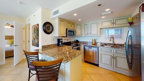 A modern kitchen with granite countertops, stainless steel appliances, and light-colored cabinetry. - Beautiful beachfront getaway with balcony, pools, tennis, and WiFi (Panama City Beach)