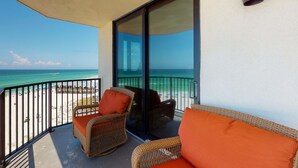 A balcony with wicker furniture and a view of the beach and ocean. - Beautiful beachfront getaway with balcony, pools, tennis, and WiFi (Panama City Beach)