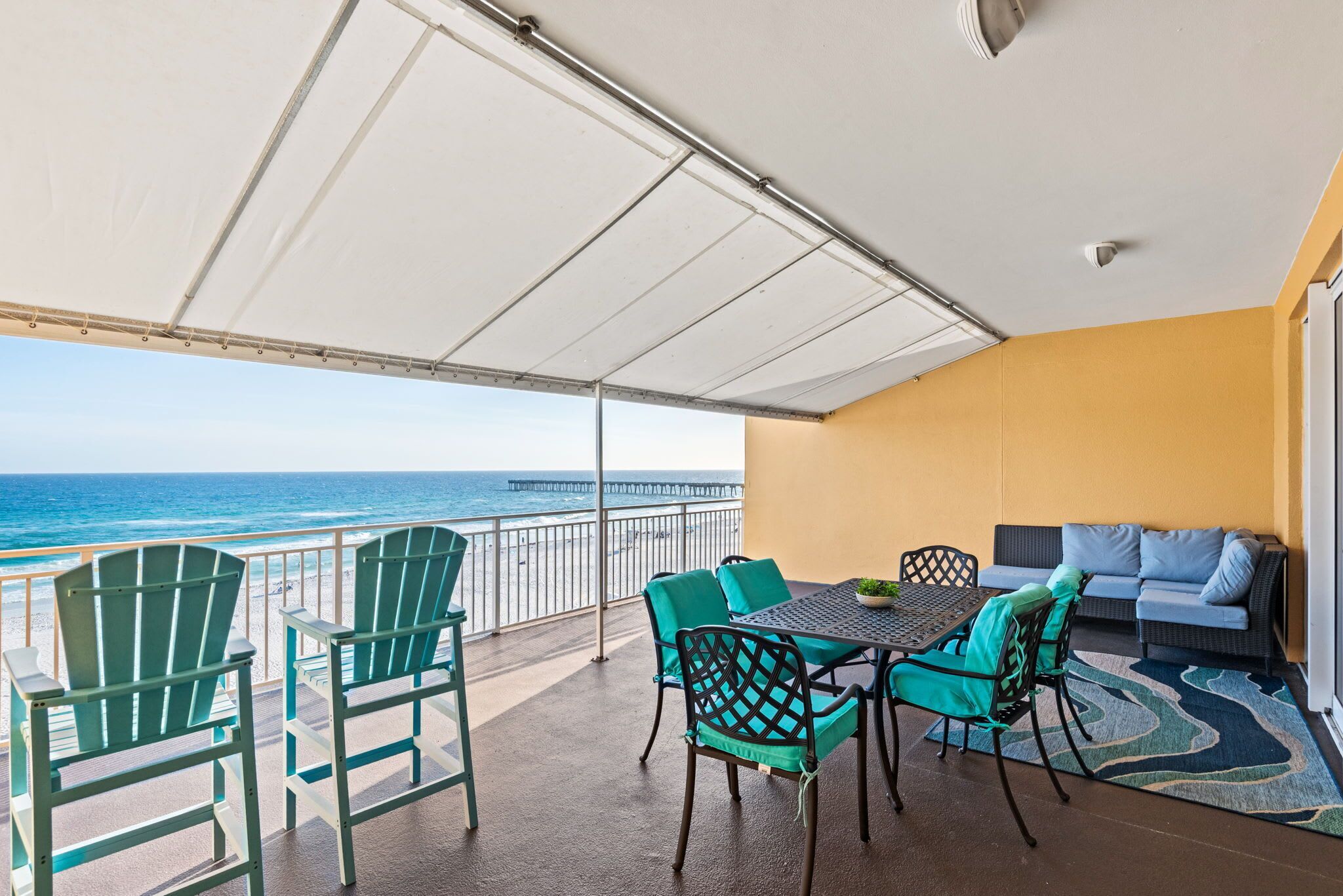 A balcony with chairs, a table, and a sofa overlooking the ocean.