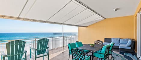 A balcony with chairs, a table, and a sofa overlooking the ocean.