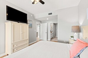 Quarto com cama, televisão, guarda-roupa e ventoinha no teto.