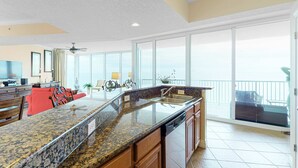 A spacious kitchen with granite countertops, wooden cabinets, and a large island with a sink. - Nautical getaway just steps from the beach with pool & hot tub (Panama City Beach)