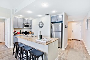Eine moderne Küche mit Granit Arbeitsplatten, Edelstahlgeräten und einer Bar mit Sitzgelegenheiten.