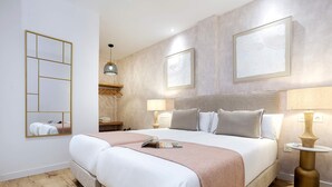Habitación de hotel con una cama grande, lámparas de noche, un espejo y obras de arte en las paredes.