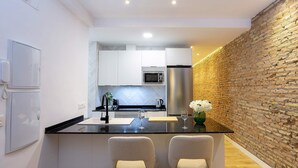 Una cocina moderna con armarios blancos, encimera negra y dos taburetes de bar.