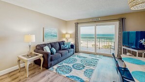 Un salon avec un canapé, une table basse, un téléviseur et une vue sur la plage.