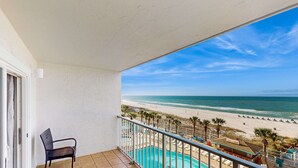 Un balcon avec vue sur la plage, une piscine et une chaise.