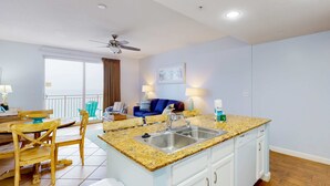 A compact kitchen with a granite countertop, white cabinets, and a built-in sink. - Beachfront condo with stunning Gulf views, beach access, pool, balcony & AC (Panama City Beach)