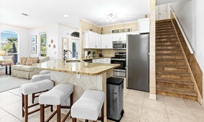 A modern kitchen with a central island, stainless steel appliances, and a wooden staircase. - Gorgeous coastal private home, close to everything and shared pool (Miramar Beach)