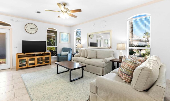 A living room with a television, sofa, coffee table, and a ceiling fan. - Gorgeous coastal private home, close to everything and shared pool (Miramar Beach)