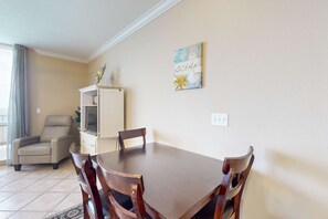 Un coin repas avec une table et des chaises en bois, un buffet blanc et un fauteuil beige.