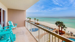 A balcony with turquoise chairs, a pool, and a beach view. - Gorgeous beachfront condo, shared pool and beach access (Panama City Beach)
