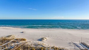 A beach with a wooden boardwalk leading to the water, sandy dunes, and a clear blue sky. - Elegant, Gulf-Front Condo w/ Large Balcony, Beach Access & Shared Pool/Gym (Perdido Key)