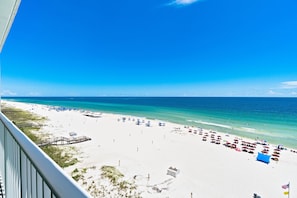 Ein Strand mit weißem Sand, klarem, blauem Wasser und einem hölzernen Steg.